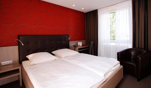 哥廷根仁斯切酒店的一间卧室设有一张大床和红色的墙壁