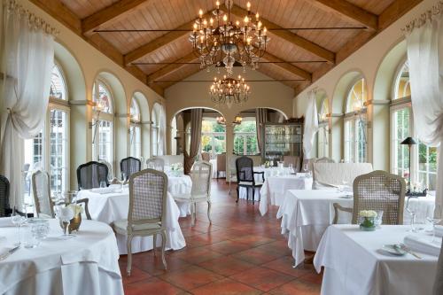 林道维里诺酒店的餐厅配有白色的桌椅和吊灯