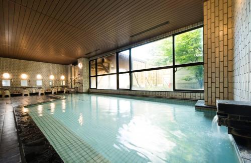 信浓七巧板酒店的一座大型游泳池,位于一座带窗户的建筑内