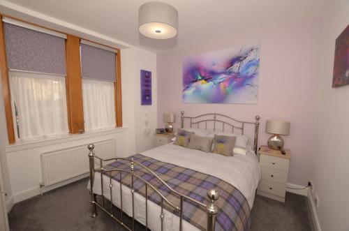 因弗内斯The Stags Head Apartment的卧室配有一张床,墙上挂有绘画作品