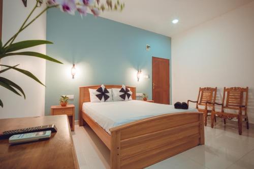 尼甘布卡布奇诺酒店的卧室配有一张床、一张桌子和椅子