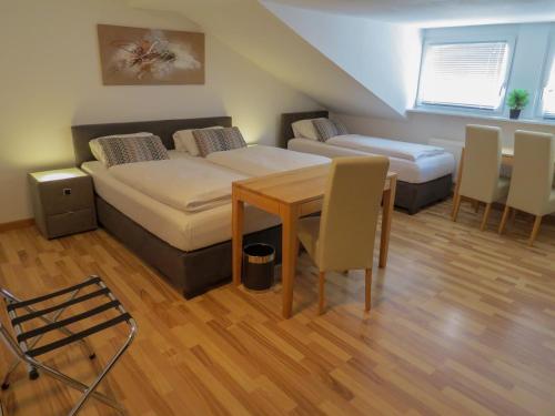 梅特拉赫萨尔布里克梅特拉赫酒店的一间设有两张床和一张桌子及椅子的房间