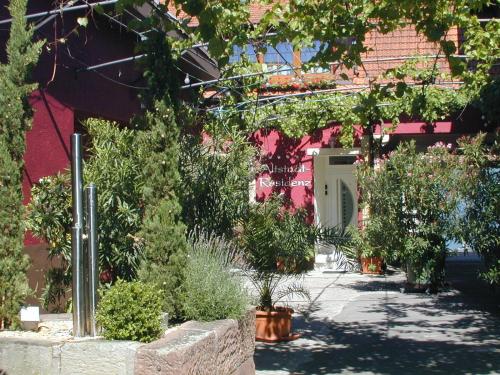 韦因斯特拉塞地区瓦亨海姆奥斯塔德曼茨旅馆的种有盆栽植物和粉红色建筑的花园