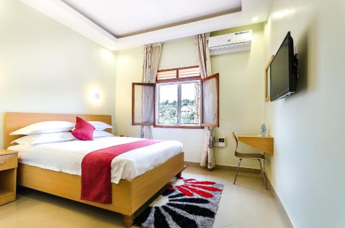 坎帕拉Nyumbani Hotel的一间卧室设有一张床、一台电视和一个窗口。