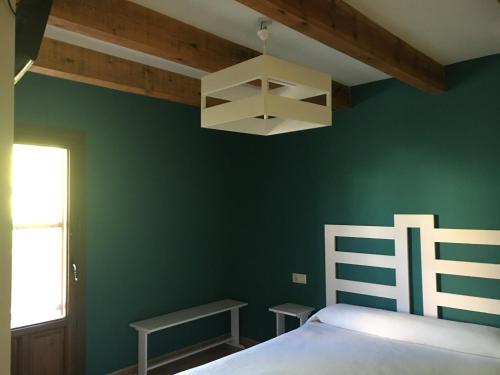 GalveHotel Rural Casa La Era的一间卧室设有绿色的墙壁、一张床和一个吊灯。