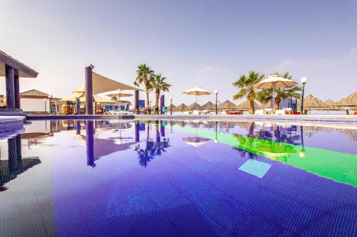 迪巴皇家海滩度假酒店的棕榈树和遮阳伞度假村的游泳池