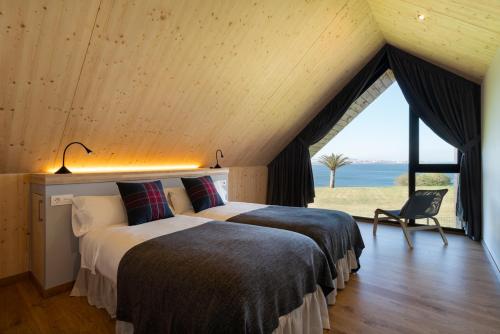拉科鲁尼亚Cabañas de Canide的一间带两张床的卧室,享有海景