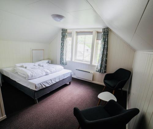 居德旺恩Gudvangen Budget Hotel的卧室配有床、椅子和窗户。