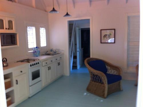 Five Islands VillageSpice Cottage的厨房配有白色橱柜和蓝色椅子