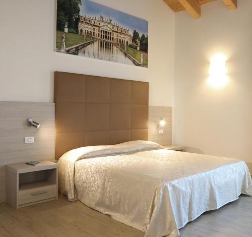 马尔孔滕塔Agriturismo Corte Foscara的卧室配有一张床,墙上挂有绘画作品