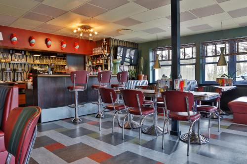 阿尔贝特斯隆维特罗浦汽车旅馆的一间设有红色椅子的餐厅和一间酒吧