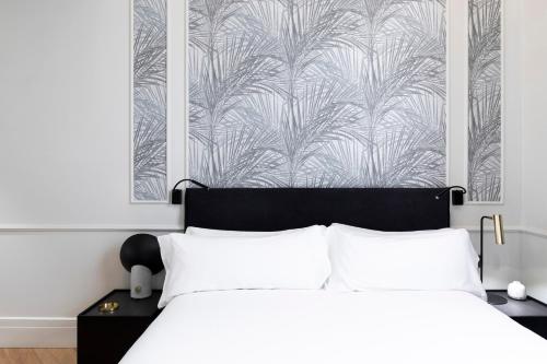 巴塞罗那Maldà Singular Hotel的一间卧室配有一张带白色床单和壁纸的床。