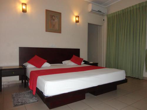 科伦坡夏利马尔酒店的一间卧室配有一张带红色枕头的大床