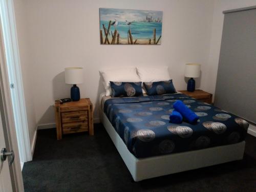 林肯港Laguna View的卧室配有蓝色泰迪熊,坐在床上