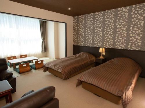 郡山Itoen Hotel Bandai Mukaitaki的一间卧室配有两张床、一张桌子和一张沙发