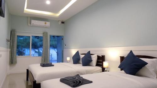 沙美岛沙美岛蓝月宾馆的一间卧室配有两张带蓝色枕头的床和窗户。