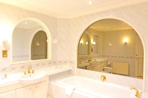 伊斯特布恩Fairways的带浴缸、水槽和镜子的浴室