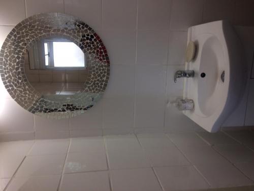 斯特兰德Romilly Beach Apartment的浴室设有圆镜和小便器