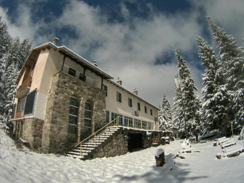 潘尼希特хижа "Скакавица"的雪地中的一座建筑,有雪覆盖的树木