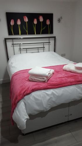 什鲁斯伯里Ruth's Refresh的一张带白色毛巾和粉红色鲜花的床铺