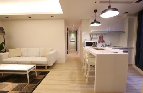 台北Lienmei 月租房的厨房以及带沙发和桌子的客厅。