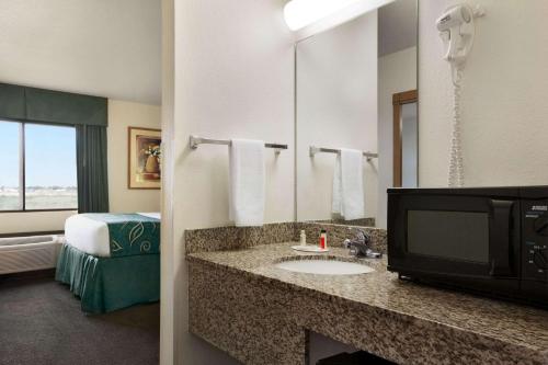 佩科斯Travelodge by Wyndham Pecos的酒店客房设有带水槽的浴室和电视。