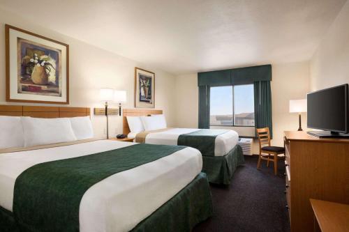 佩科斯Travelodge by Wyndham Pecos的酒店客房设有两张床和一台平面电视。