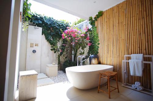塞米亚克巴厘阿斯里巴图贝里别墅酒店的浴室配有浴缸和鲜花淋浴