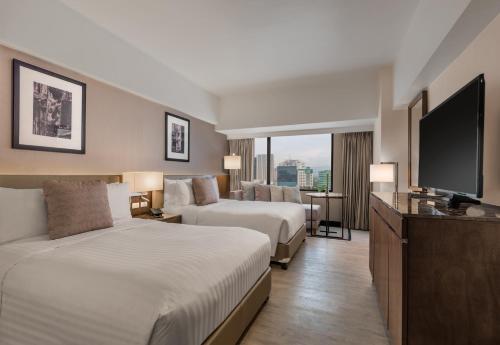 宿务Seda Ayala Center Cebu的酒店客房设有两张床和一台平面电视。