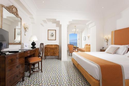 索伦托安巴夏托理大酒店的酒店客房配有一张床、一张书桌和一台电视。