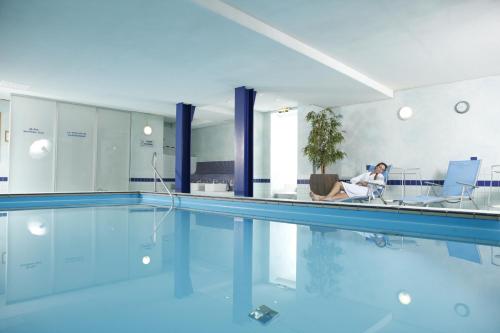 哥廷根仁斯切酒店的坐在游泳池旁椅子上的女人