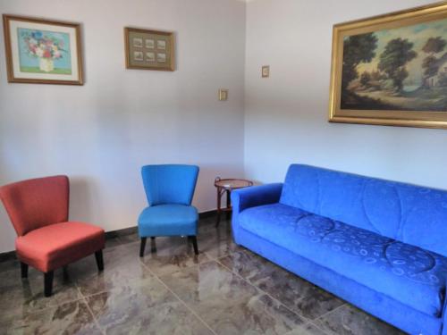 佩兹迪格雷科Villa Camilla的客厅配有蓝色的沙发和两把椅子