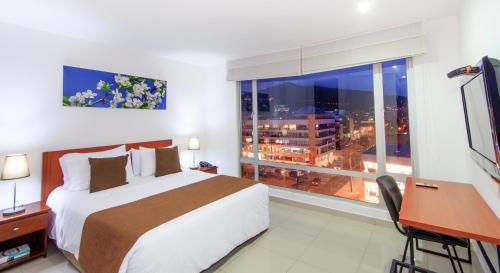 波哥大122广场公寓式酒店的一间卧室配有一张床、一张书桌和一个窗户。