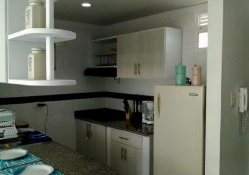 圣玛尔塔Apartamento con Piscina En el Rodadero Santa Marta Colombia的厨房配有白色橱柜和白色冰箱。