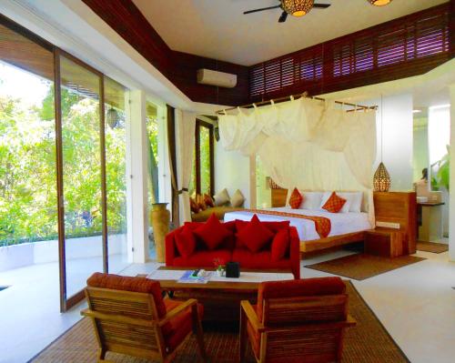 乌布Cahaya Indah Villas的一间卧室配有一张床、一张沙发和椅子