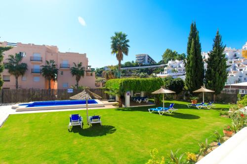 内尔哈Apartamentos Turisticos Almoraide Suites的一个带草坪椅和遮阳伞的庭院