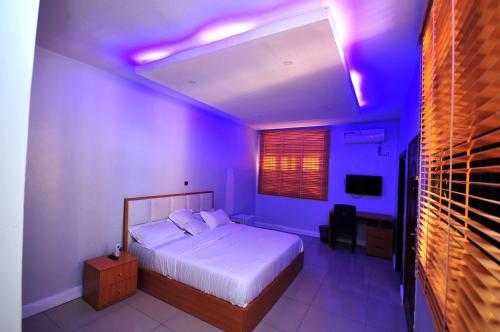 拉各斯HIS Dulce Apartments的一间卧室配有一张带紫色灯的天花板床。