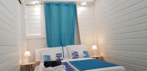 旧阿比唐Gîte Akwarel的一间卧室配有蓝色窗帘和一张床