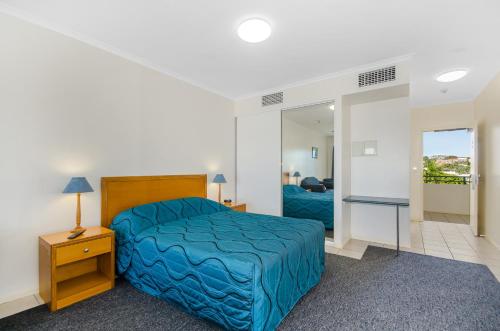 汤斯维尔Madison Ocean Breeze Apartments的一间卧室配有蓝色的床和镜子