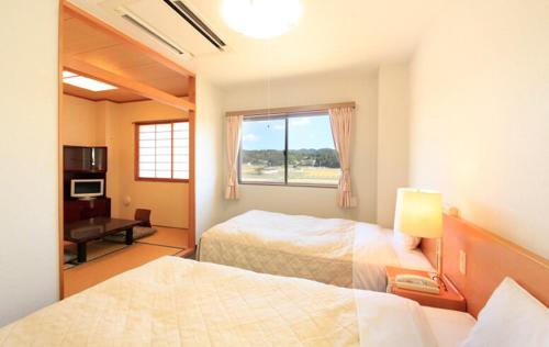登米市Hotel Bouenkaku的一间卧室设有两张床、一个窗口和一张书桌
