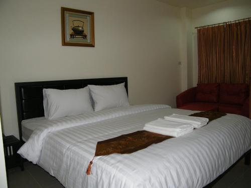 乌汶房迪1号大厦酒店的一张配有白色床单和红色椅子的大床