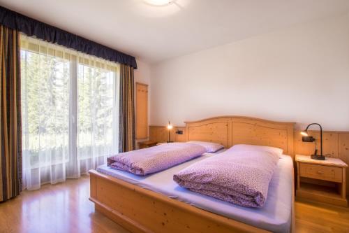 圣维吉利奥Ciasa Isidor的一间卧室设有两张床和大窗户
