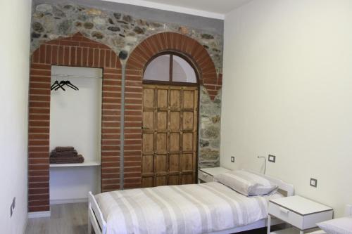 Settimo VittonePassaggio a Nord Ovest的一间卧室设有一张床和砖墙