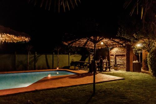 圣费尔南多Santa Teresita Boutique Hotel的游泳池在晚上配有遮阳伞