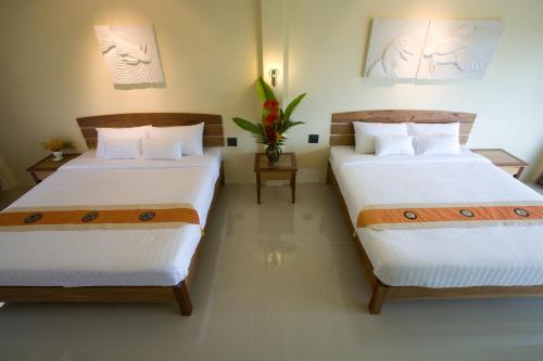 象岛帕拉度假酒店的两张位于酒店客房的床,配有两张sidx sidx单人床