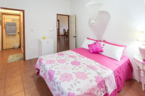 LaboriePalm View的卧室配有粉红色和白色的床以及粉红色枕头