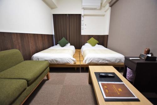 福冈Randor Hotel Fukuoka的客房设有两张床、一张沙发和一张桌子。