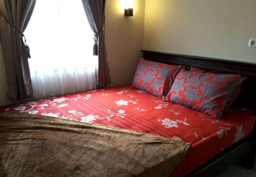 巴图Villa Sakura Kusuma Estate的一张带红色棉被的床和一扇窗户