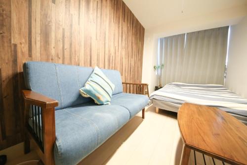 名古屋Guest House Re-worth Yabacho1 401的客厅配有蓝色的沙发和床。