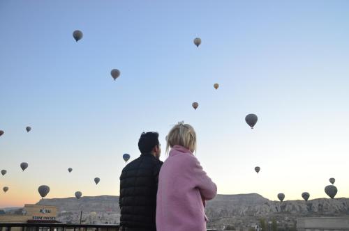 格雷梅Cappadocia Elite Stone House的男人和女人看着热气球